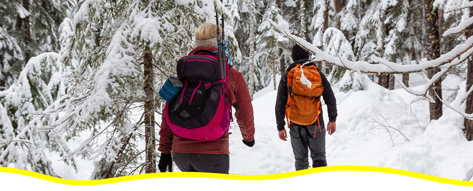 Deux personnes avec des sacs à dos, en randonnée en hiver.