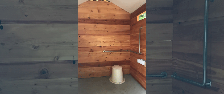L’intérieur de la toilette extérieure est muni de plusieurs barres d’appui et d’un espace pour un fauteuil roulant.