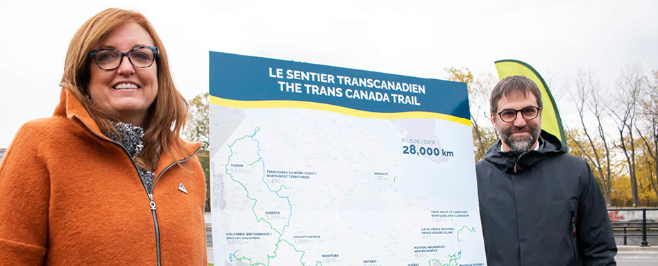 Trans Canada Trail CEO Eleanor McMahon and a trail member standing Infront of a Trans Canada Trail sign 