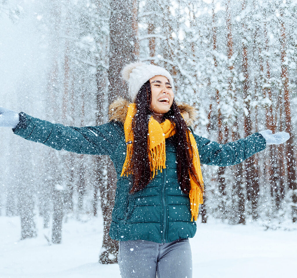 Joyful woman embracing the winter wonderland, arms outstretched on a scenic section of the Trans Canada Trail. 