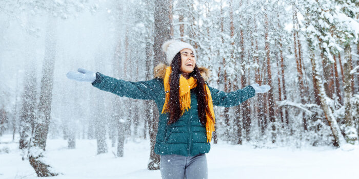 Joyful woman embracing the winter wonderland, arms outstretched on a scenic section of the Trans Canada Trail.