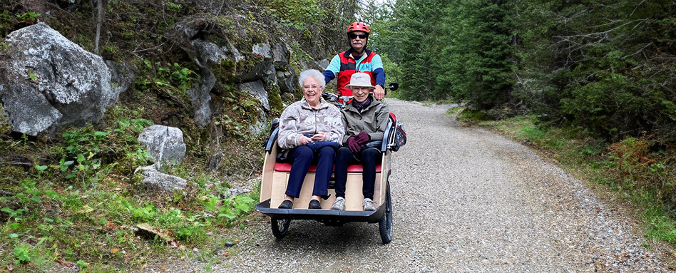 Trois personnes âgées profitant d'une balade tranquille en trishaw le long d'un sentier pittoresque.