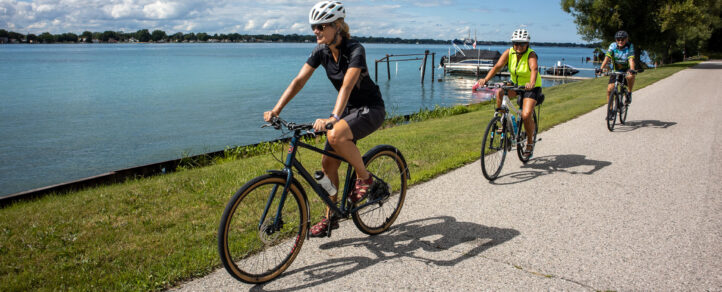 Two adult women happily riding their bikes along the Windsor Waterfront Trail