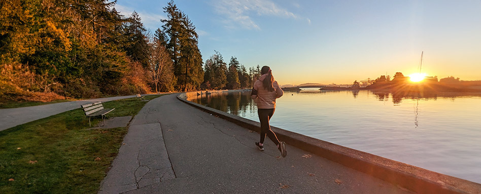 Une femme fait du jogging sur le sentier de la ville de Vancouver au bord de l'eau