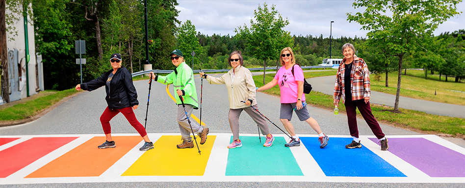 A group of adults walking across a rainbow cross walk in Quispampsis