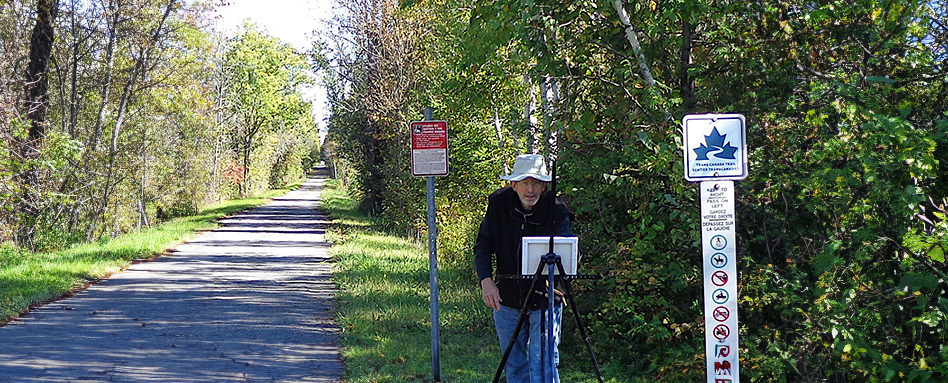 David Kearn, an artist, working on his art on the grass section of the trail