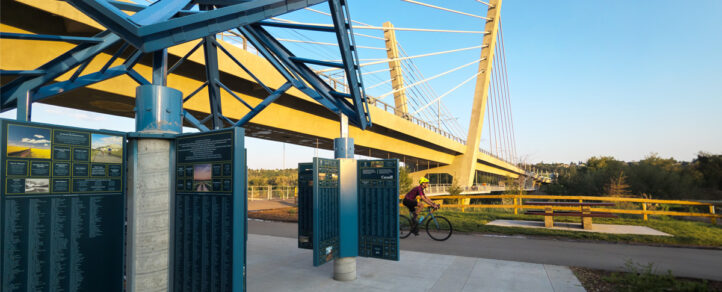 A man riding a bike under a bridge. | 