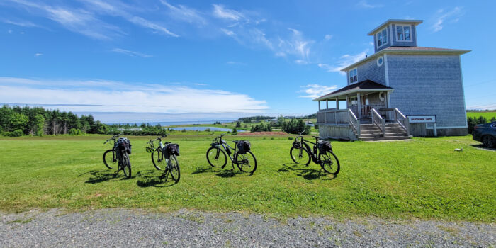 Bikes parked on a lush green lawn in Prince Edward Island overlooking the expansive water ahead | 