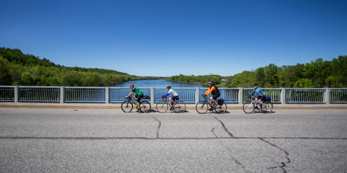 Four cyclists riding on a bridge for the Great Waterfront Trail Adventure | Quatre cyclistes chevauchant sur un pont pour la Great Waterfront Trail Adventure 