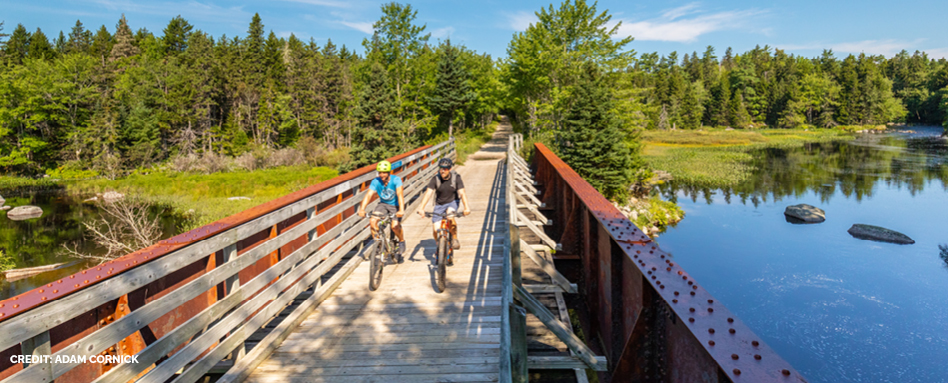 Two people biking across a bridge over a river in Chester | Deux personnes traversant à vélo un pont au-dessus d'une rivière à Chester 