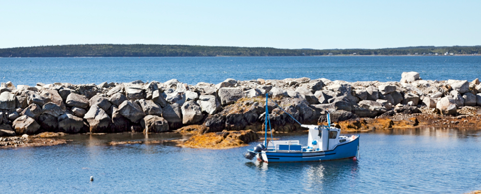 A tranquil blue fishing boat in Lunenburg, calmly situated in the water. | Un bateau de pêche bleu tranquille à Lunenburg, situé calmement dans l'eau. 