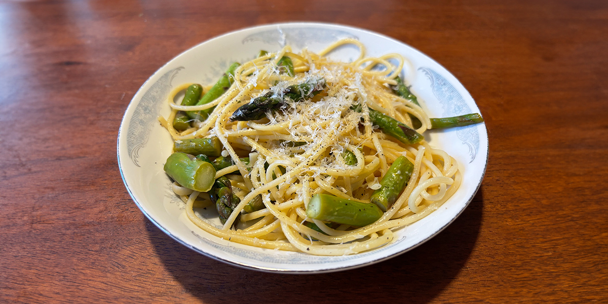 A delicious plate of asparagus pasta topped with parmesan cheese. | Une assiette de pâtes aux asperges et au parmesan