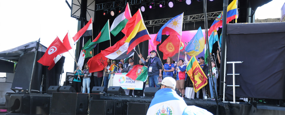 A diverse group of people on stage holding flags at Mosaïq Fest. | Un groupe diversifié de personnes sur scène tenant des drapeaux au Mosaïq Fest.