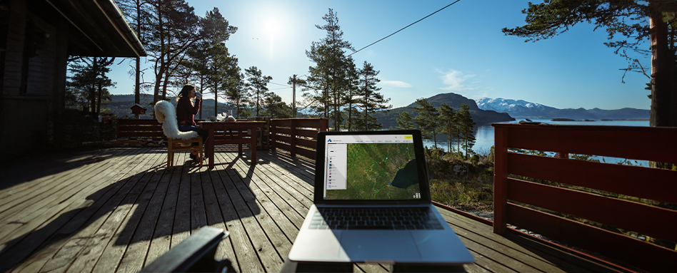 Laptop on wooden deck with mountain view, displaying Trans Canada Trail map. 