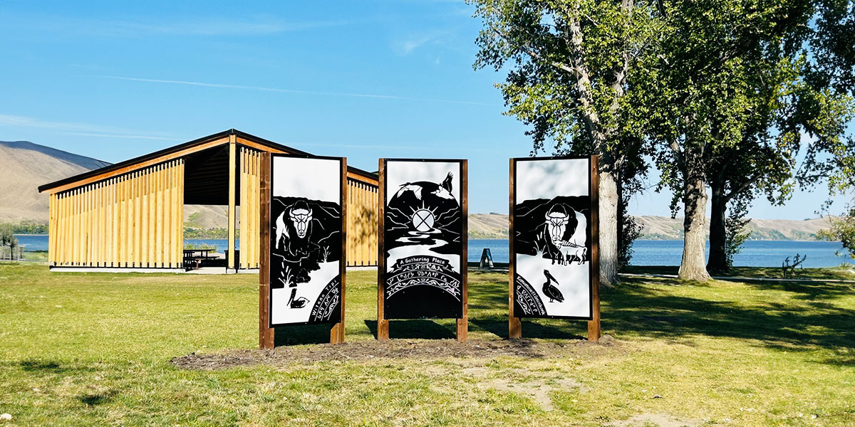 Three large black and white posters displayed on a grassy field, highlighting Indigenous culture in Echo Valley Provincial Park. Trois grandes affiches en noir et blanc affichées sur un terrain gazonné, mettant en valeur la culture autochtone du parc provincial Echo Valley.