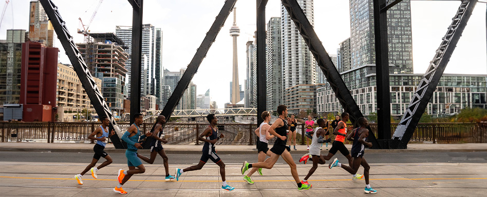 A group of runners from the Canada Running Series races across a bridge in Toronto. Un groupe de coureurs de la Canada Running Series courent sur un pont à Toronto. 