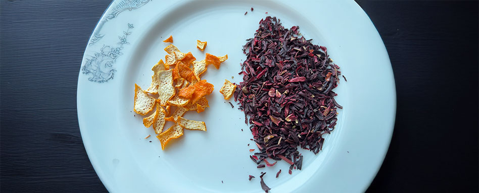 A plate featuring dried fruit, including orange peel and dried hibiscus to make Orange hibiscus tea.Une assiette composée de fruits séchés, notamment des écorces d’orange et de l’hibiscus séché, pour préparer un thé à l’hibiscus et à l’orange.