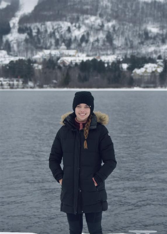 woman standing infront of wintery mountains smiling for a portrait