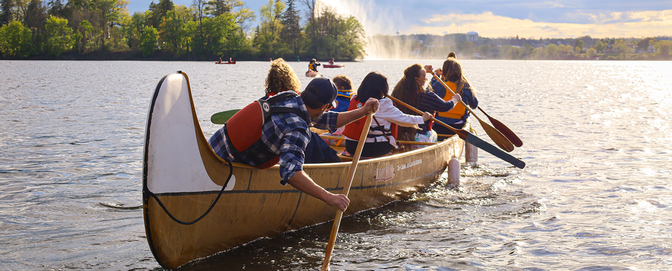 people paddling a canoe on a lake on a sunny day