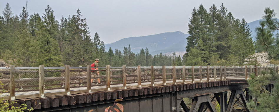 02Trestle_support image_credit Off Track Travel | Sentier Transcanadien person walking on long bridge with trees and mountains in background