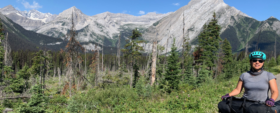 person on a bike smiling with mountain range behind