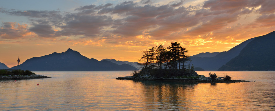 sunset overlooking mountains and small island on ocean