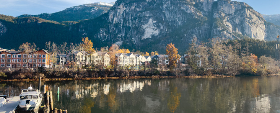 houses resting ocean-side with mountainous background