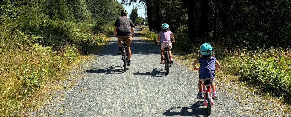 family biking on a trail with greenery