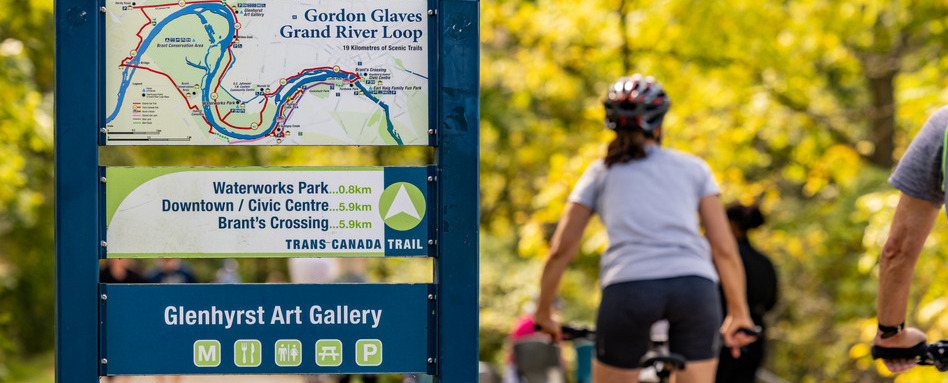 person biking on a trail with a marker sign on sunny day