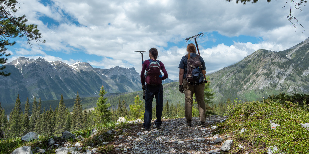 AB - High Rockies Trail Kananaskis | Sentier Transcanadien two people standing on a mountain in hiking gear on a sunny day