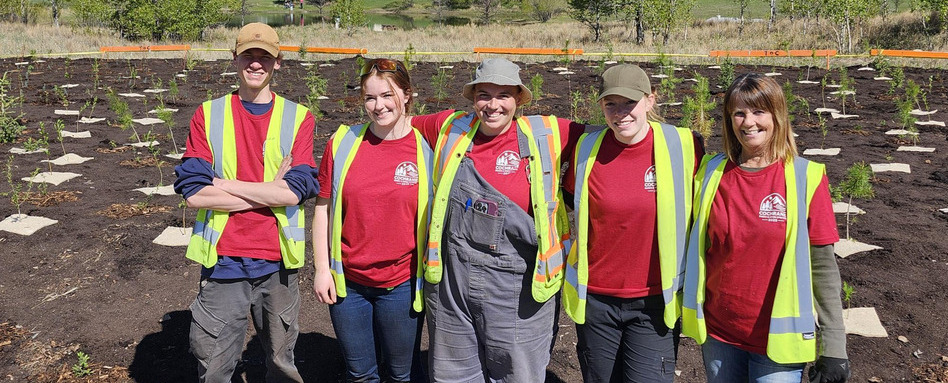 SF107127_Planting-for-Tomorow-Program-Cochrane-AB_Cochrane-Staff_credit-Angie-Basha_Web_StorySupport_Images_948x383 | Sentier Transcanadien group of people in vests smiling in tree planting gear on sunny day