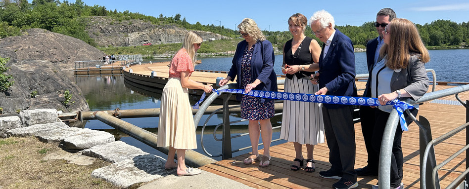 people cutting a rope on a boardwalk on sunny day