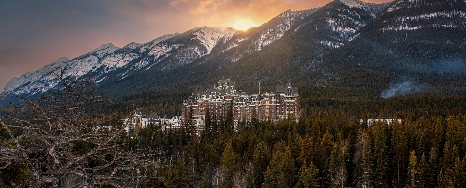 birdseye view of fairmont hotel with mountain and sunrise behind on snowy day