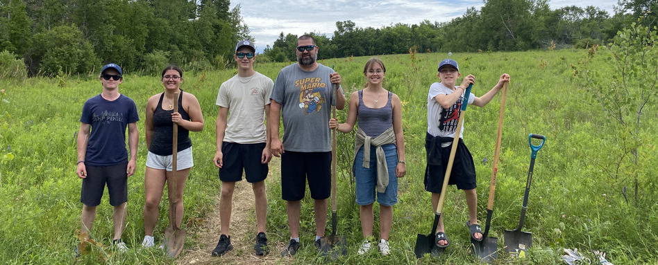people posing smiling for photo in field on cloudy day