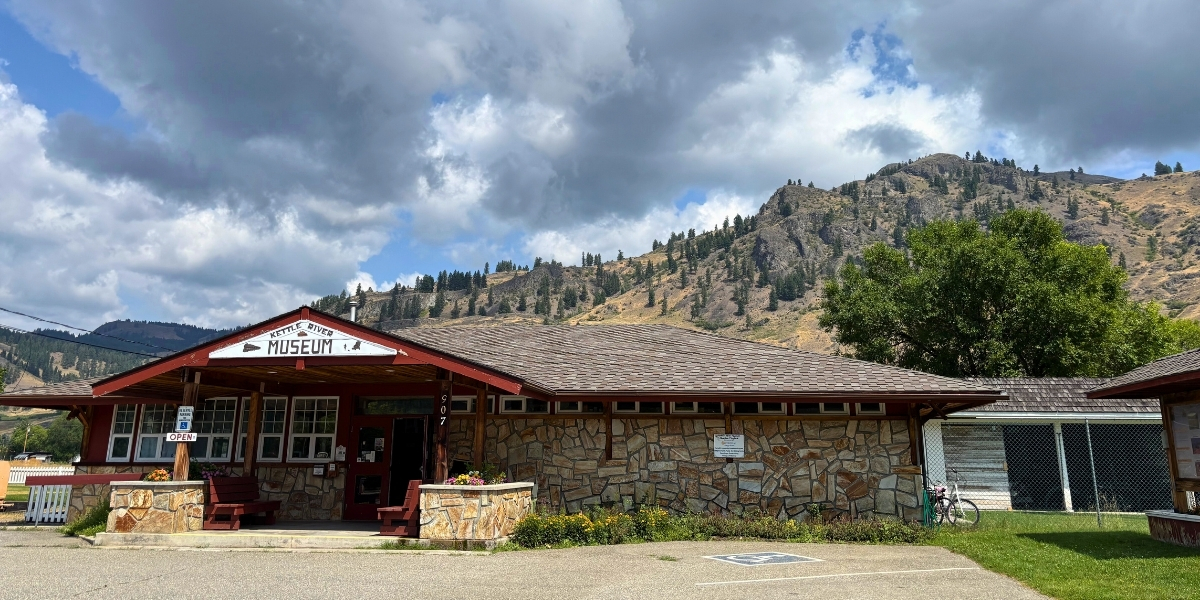 photo of large building in empty lot with mountain behind on a cloudy day