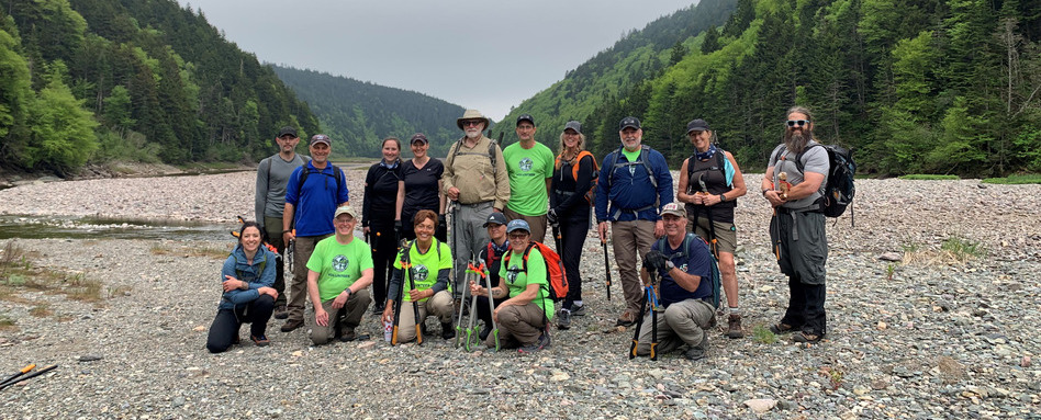01Support image_NB_Fundy Trail_SF107809_NB_Trail-Care-2025-Fundy-Hiking-Trail-Association | Sentier Transcanadien group of people in matching tshirts standing on gravel with tools and mountains behind