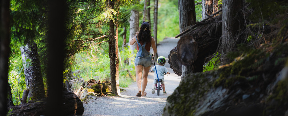 woman and child walking along a wooden trail on a sunny day