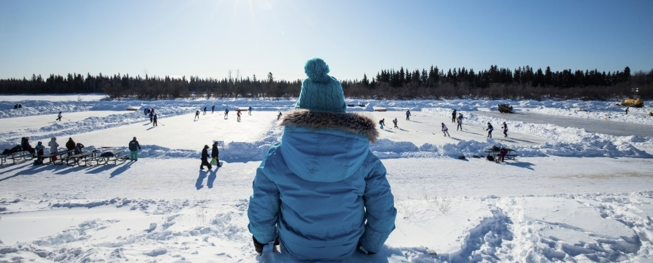 02Support image_NWT winter activities_Credit Paul Zizka and NWTT_dont use outside of NWT promotion | Sentier Transcanadien person in winter gear overlooking a skating pond on a sunny day