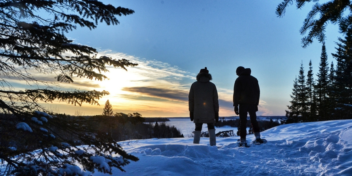 00Feature image_MB_Shel Zolkewich_winter hiking | Sentier Transcanadien two people standing in the snow overlooking a sunset