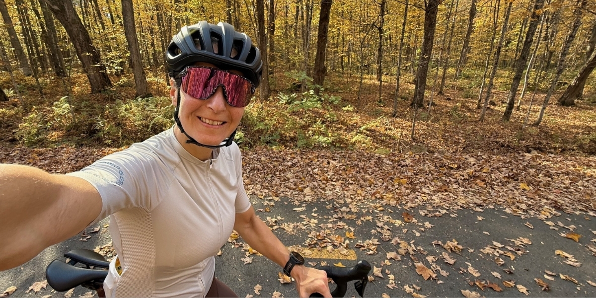 woman on a bike wearing helmet and sunglasses on a leaf-covered trail