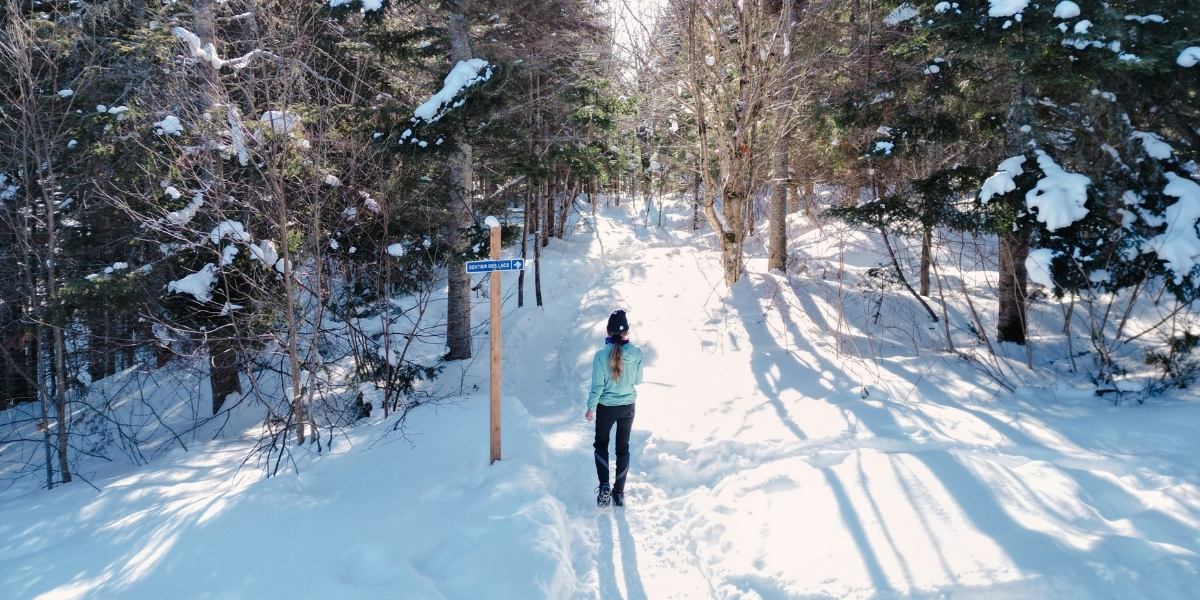 00Feature image_QC_Sentier des Caps_Web story_credit Au Québ | Sentier Transcanadien woman walking on snowy trail on sunny day