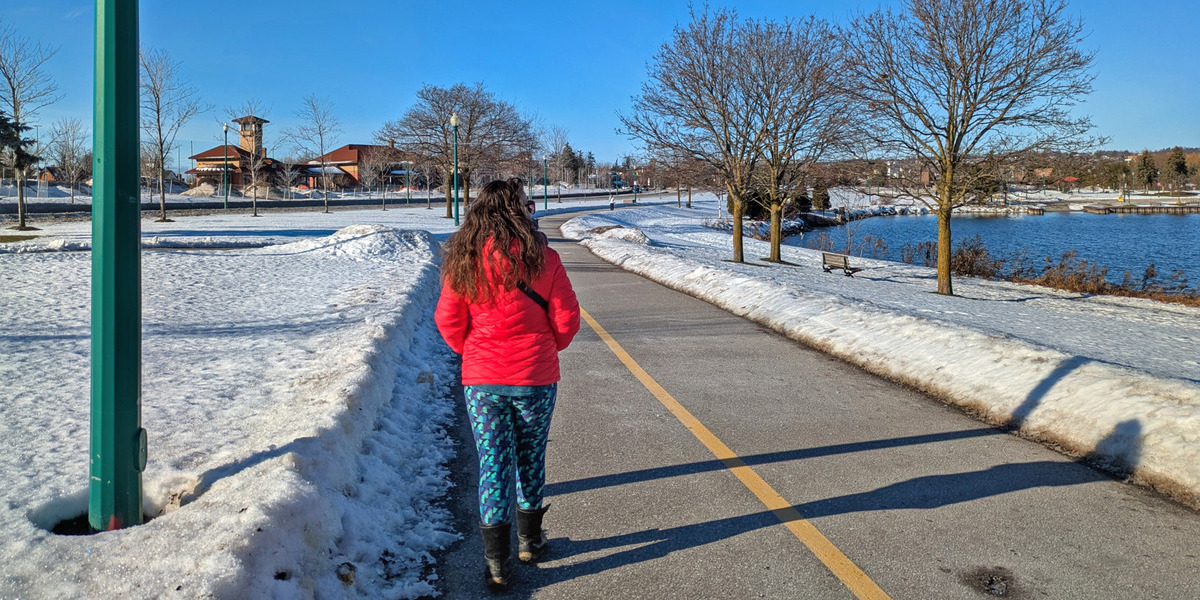 00Feature image_Stephanie Mayo_Barrie_waterfront | Sentier Transcanadien woman walking on a snowy bike trail next to waterfront on sunny day