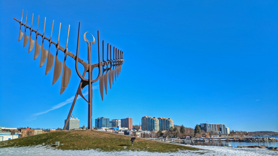large spirit catcher statue facing city skyline