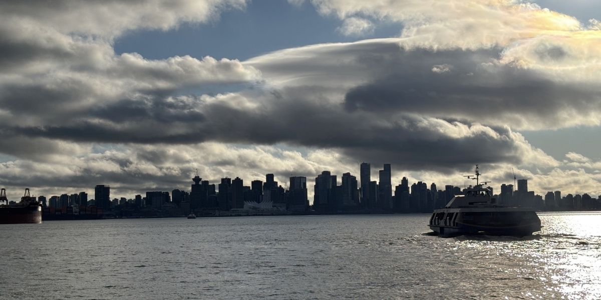 skyline view of city and ferry boat on open water on a cloudy day