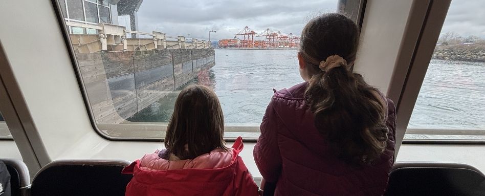 two girls on a boat overlooking water and bridge
