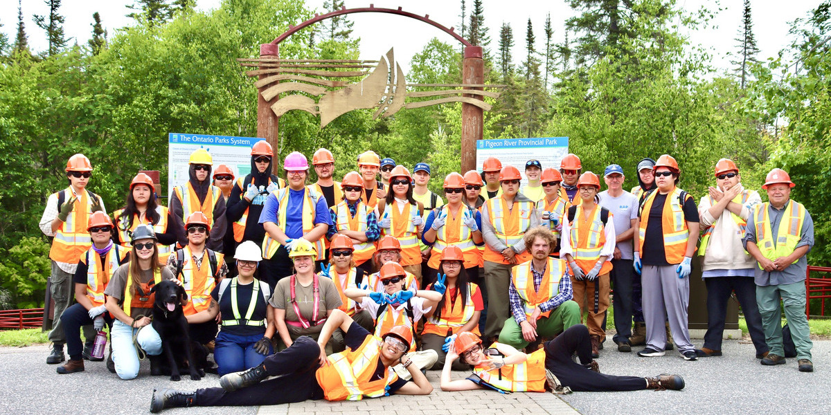group of people in hazard vests standing in parking lot on a sunny day