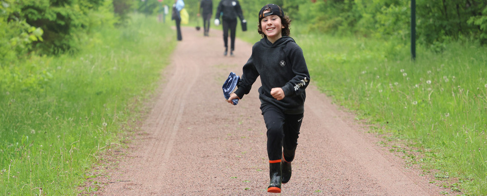 boy running on a dirt trail smiling