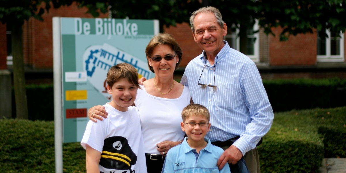 00Feature image_Generational giving Claudia Laroye_credit Claudia Laroye_cannot use for other pieces | Sentier Transcanadien Family of four posing outdoors: a grandmother and grandfather with two smiling boys in front of a signboard that reads De Bijloke.