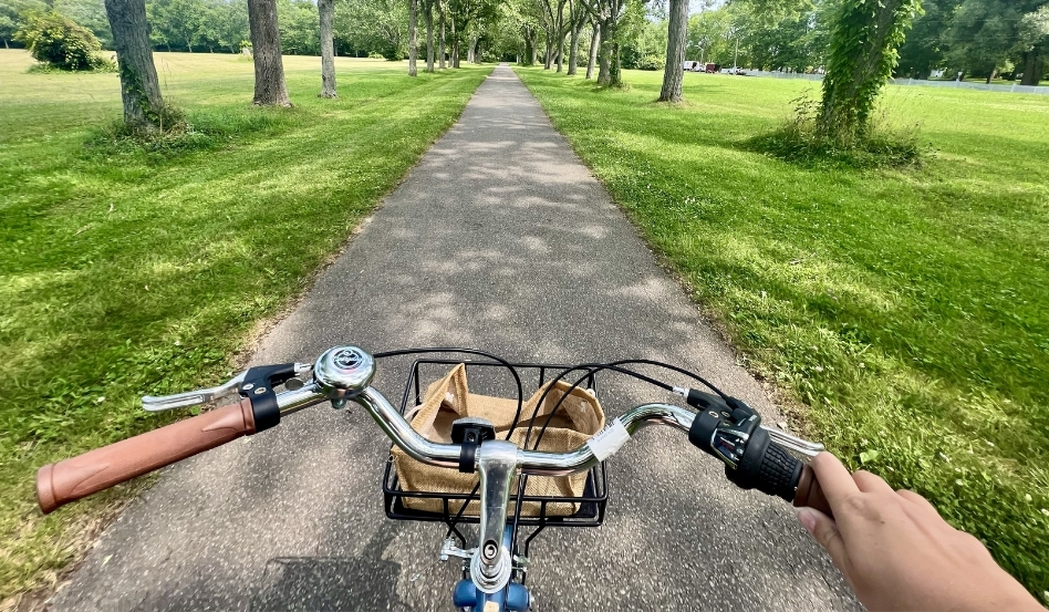 POV of someone riding bike on paved trail on a sunny day