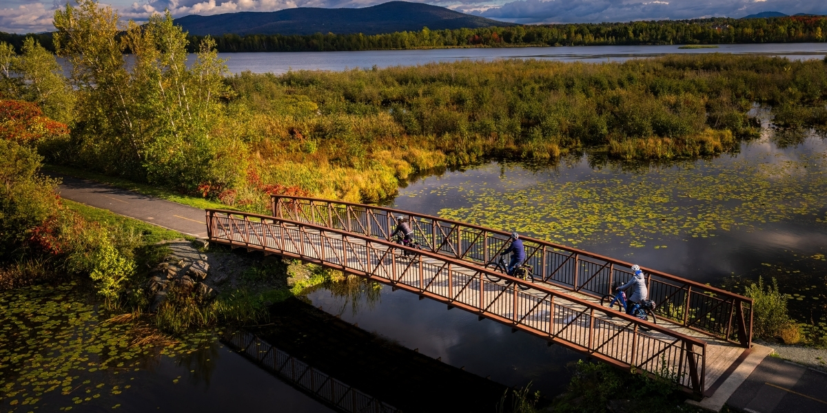 birdseye of a bridge over a marsh with greenery and rolling hills behind
